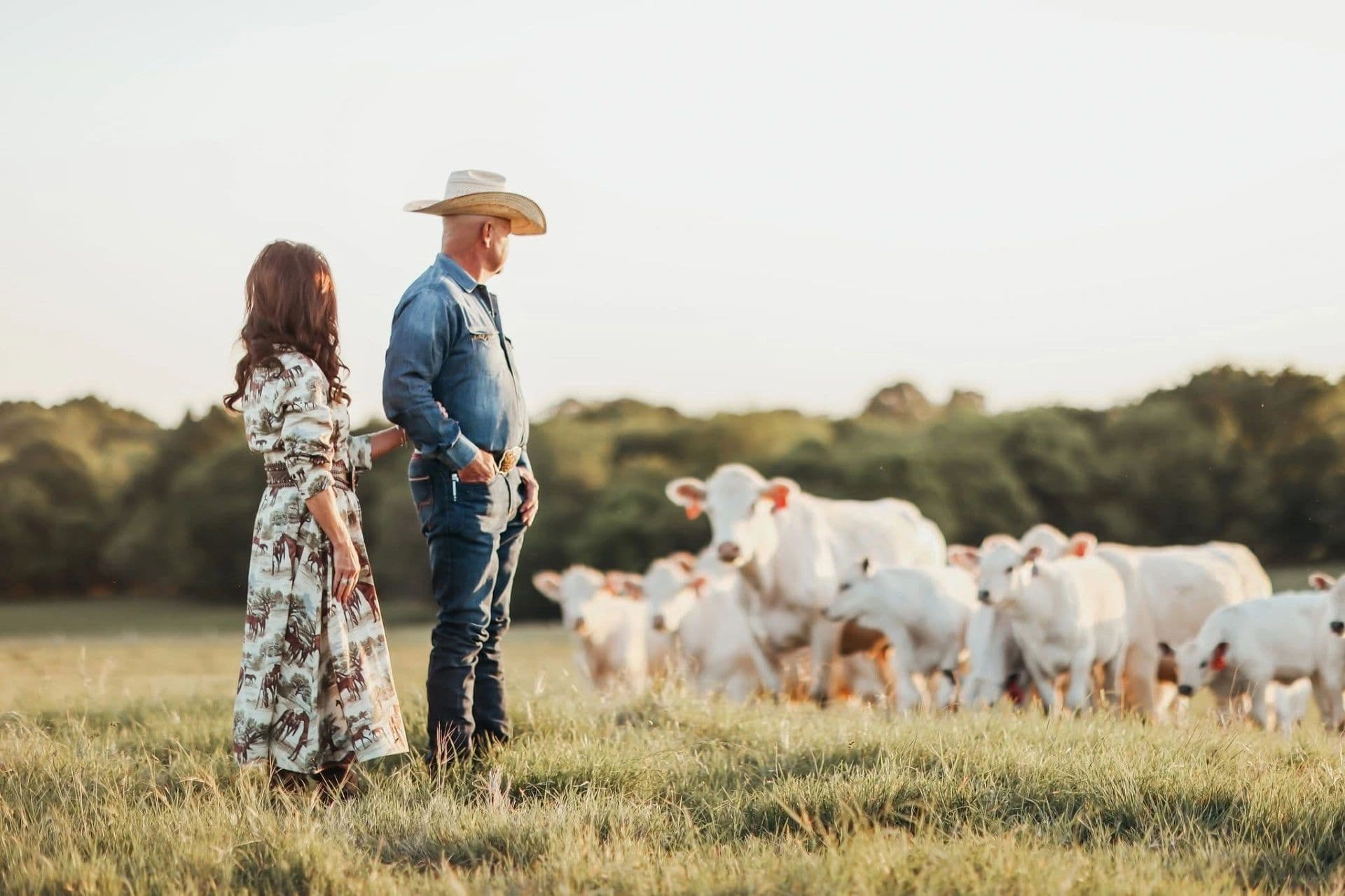 Kelly and Donna Hardman standing in a pasture at sunset watching over their cattle herd.